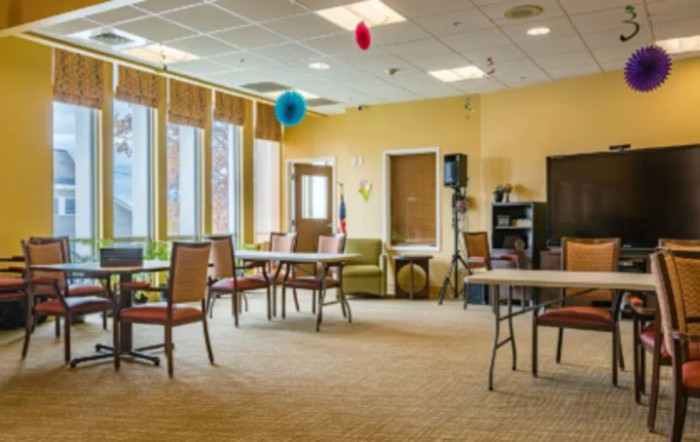 A spacious room with tables and chairs, decorated with balloons.