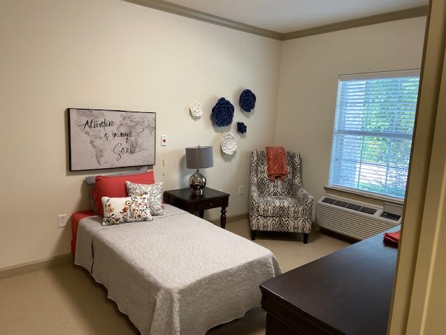 A cozy bedroom with a single bed, accent chair, and wall decorations.