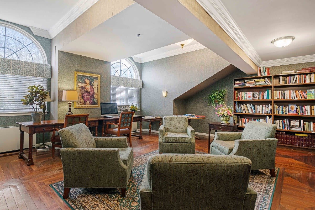 A cozy library room with armchairs and bookshelves.