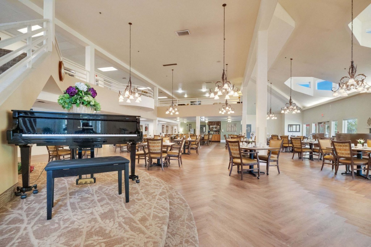 Elegant dining area with a grand piano and chandeliers.