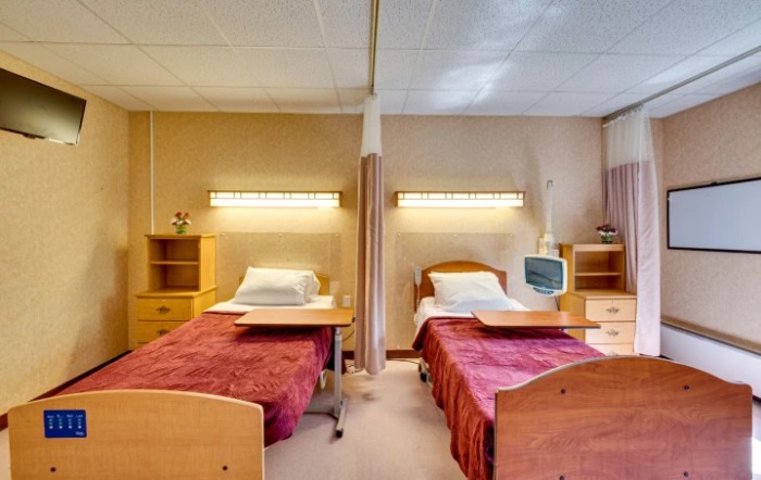A shared hospital room with two beds and medical equipment.