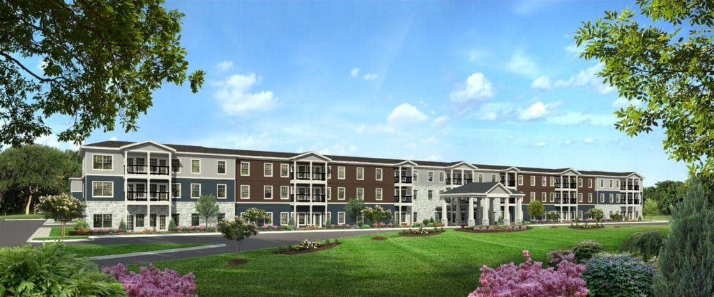 A modern residential apartment complex with a well-maintained lawn and clear blue sky.