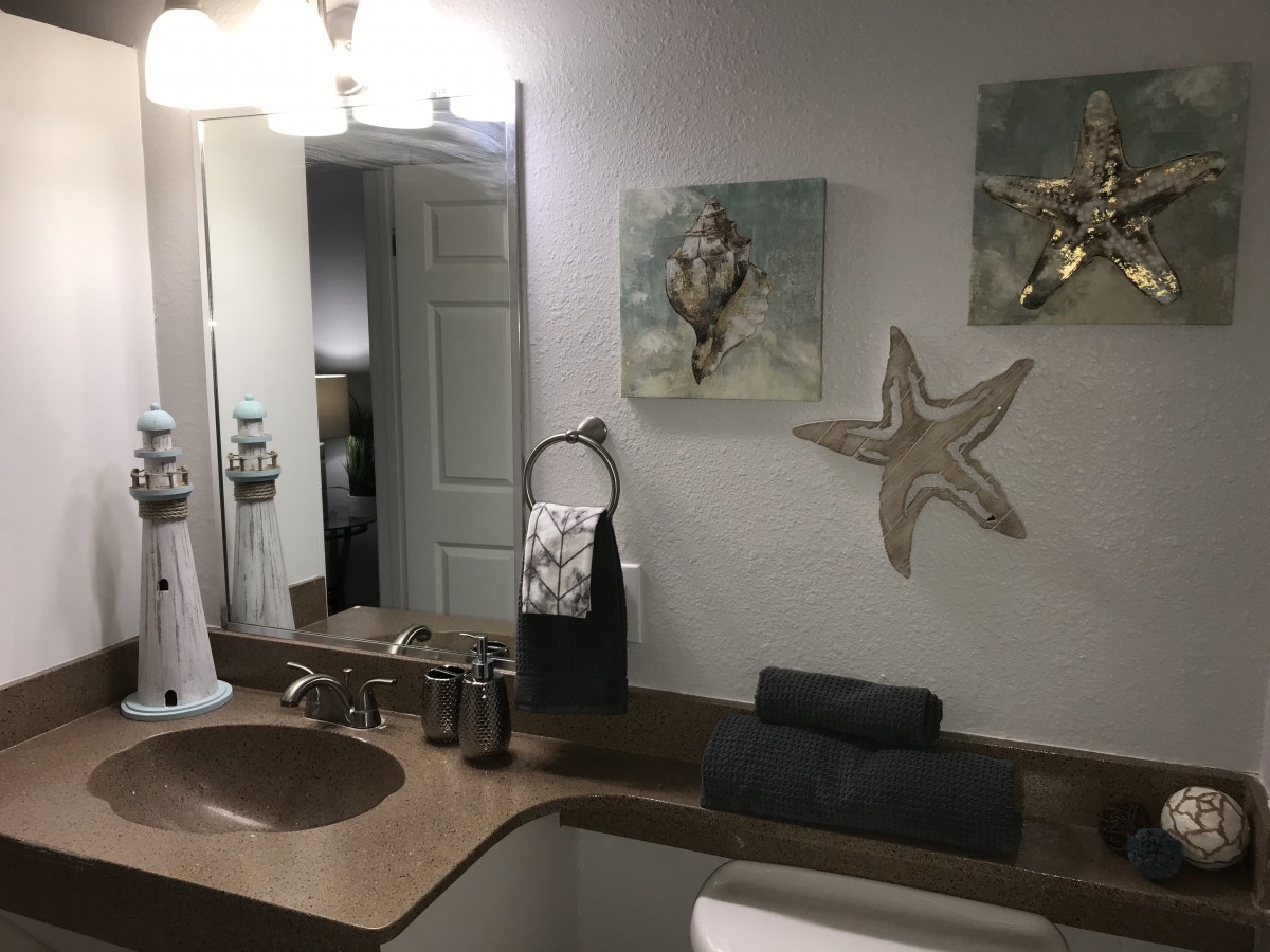 A neatly arranged bathroom with starfish-themed decor and a modern sink area.