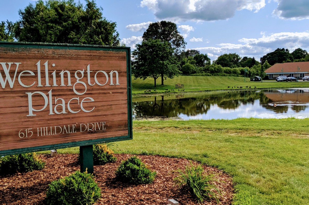 Entrance sign for Lexington Place by a scenic pond.