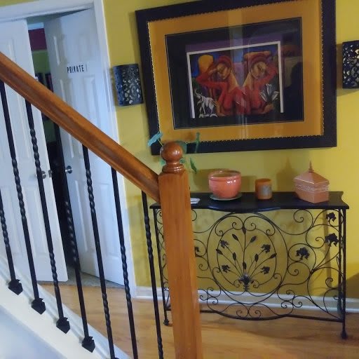 A cozy interior featuring a staircase with wooden railings, adorned by a vibrant yellow wall with artwork above a decorative console table.
