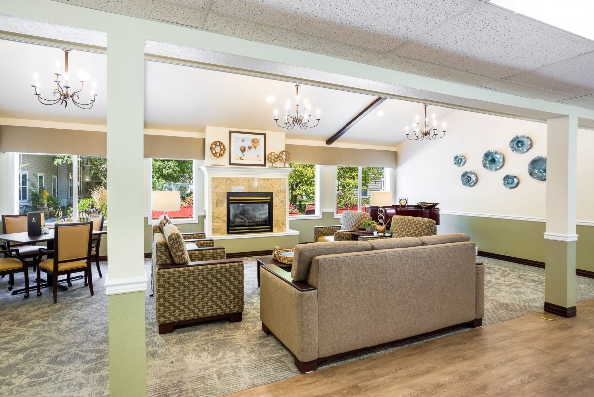 A spacious and modern living room featuring a central fireplace, comfortable sofas, and large windows providing ample natural light.