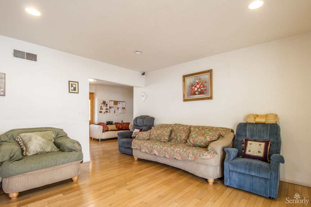A cozy living room featuring a set of sofas and armchairs on a wooden floor, decorated with wall art.