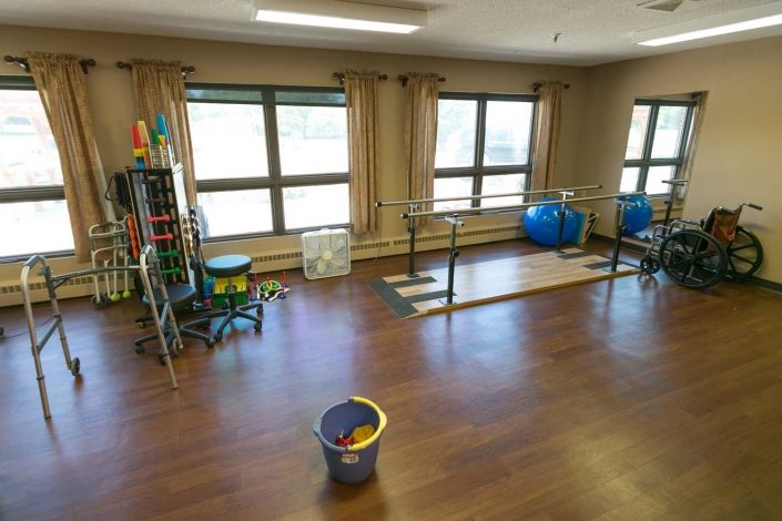 A physical therapy room with exercise equipment and parallel bars.