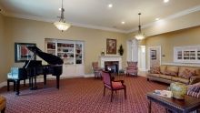A spacious living room with a grand piano, elegant furnishings, and a cozy fireplace.