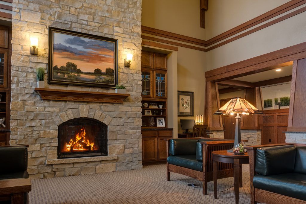 A cozy living room with a stone fireplace, an armchair, and warm lighting.
