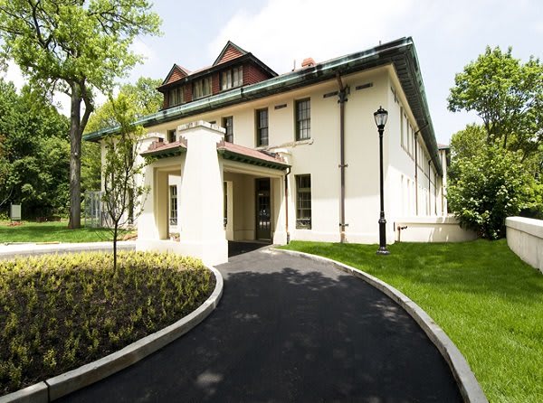 A beautiful residential house surrounded by a lush garden with a winding pathway.