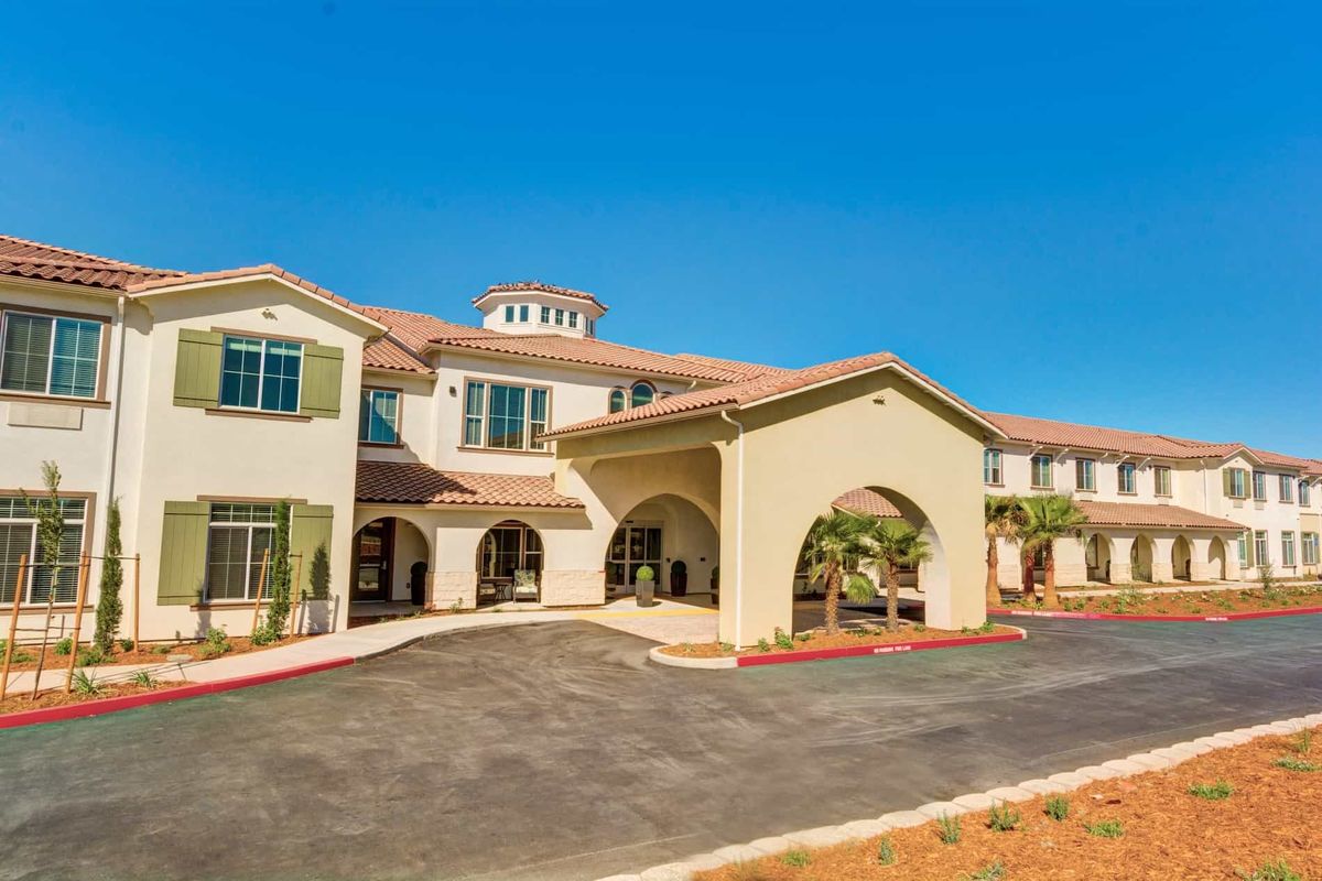 A sunny view of a two-story residential building with palm trees and a welcoming entrance.