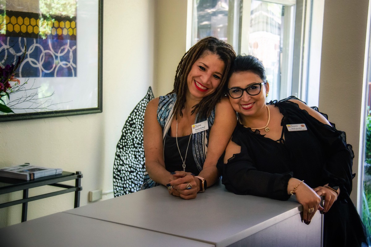 Two friends smiling and posing together indoors.