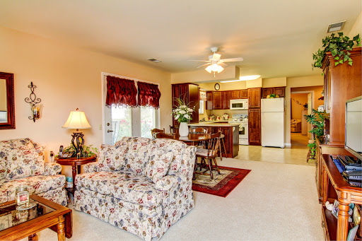 A cozy open concept living room and kitchen featuring floral furniture and warm lighting.