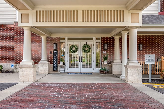 The entrance of a building decorated with wreaths and a welcome sign.