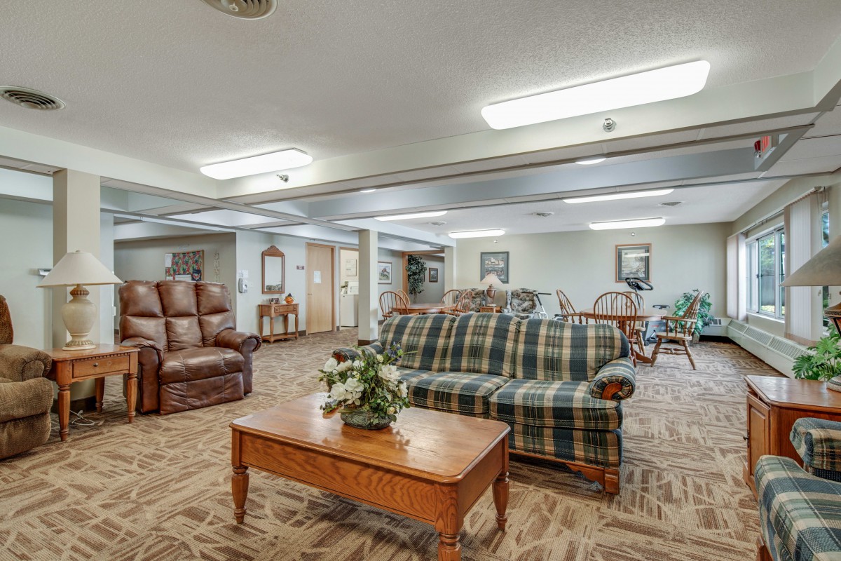 A cozy living room with a plaid sofa, armchair, and wooden coffee table.