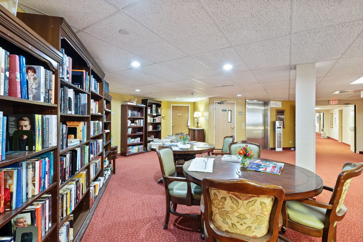 A cozy library reading room with bookshelves and a table surrounded by chairs.