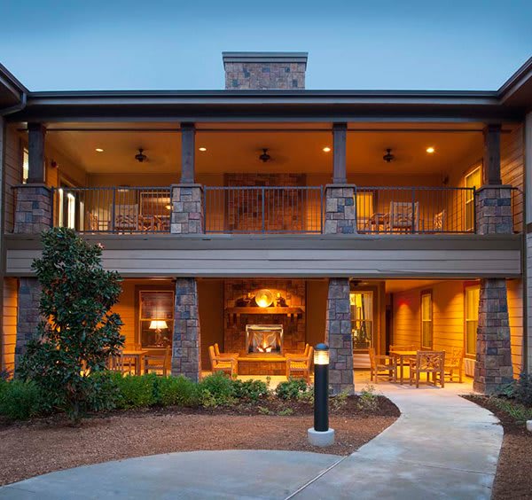A beautifully lit modern house with a spacious porch and well-maintained landscaping.