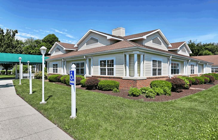 A suburban residential building with a well-maintained lawn and clear blue sky.