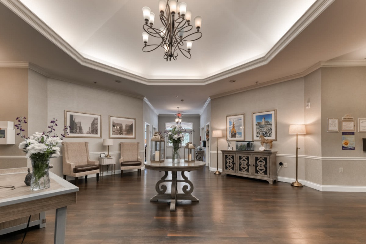 An elegant lobby with a central table, chandelier, and tasteful decor.