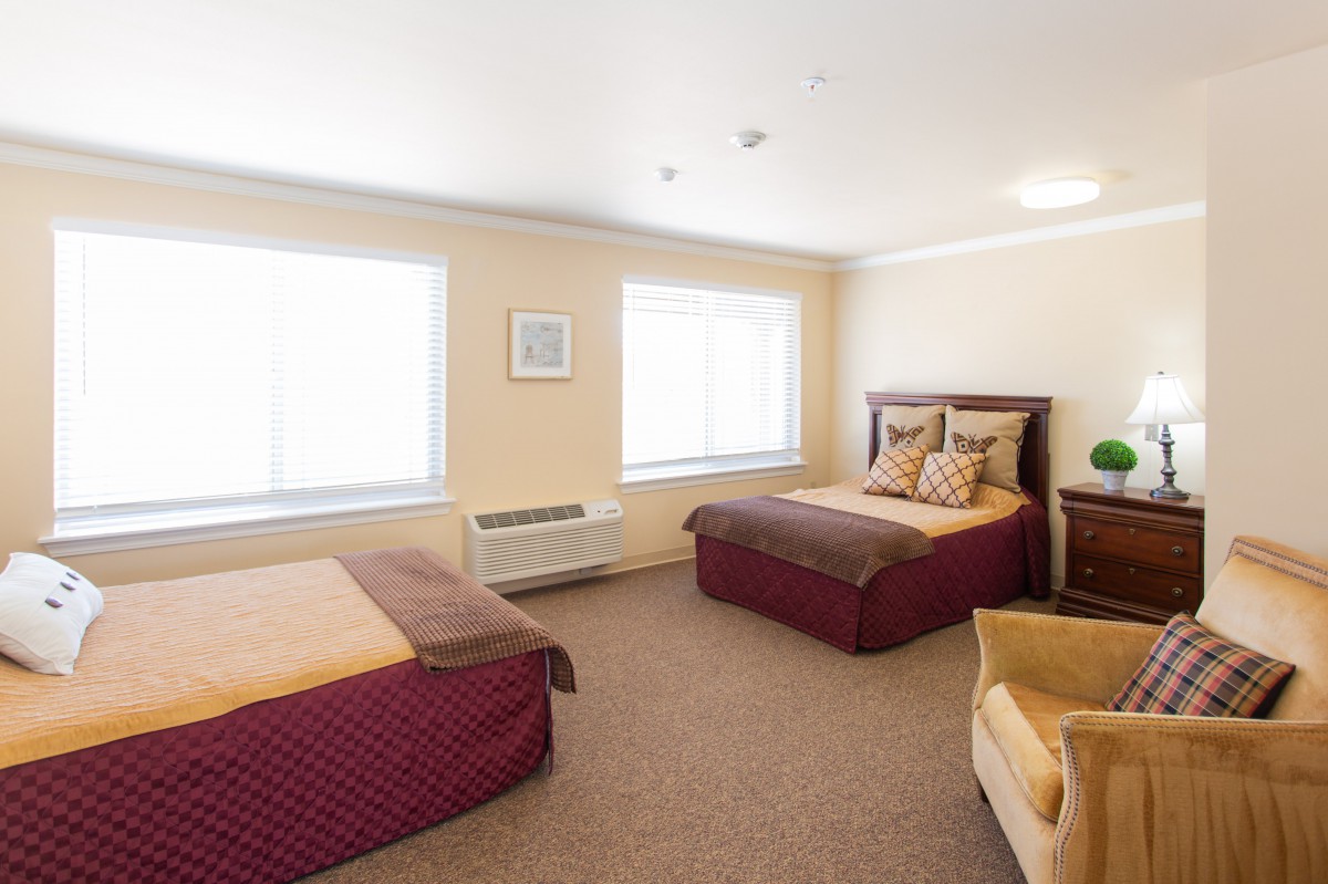 A cozy hotel room with two double beds and soft lighting.