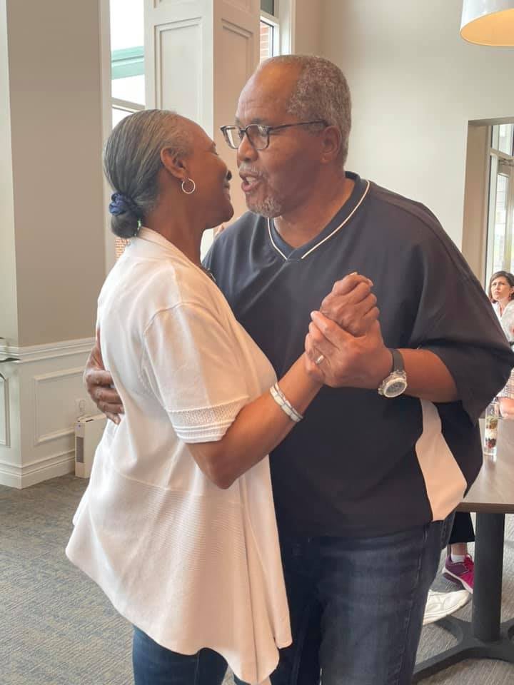 An elderly couple sharing a joyful dance indoors, embracing affection and togetherness.