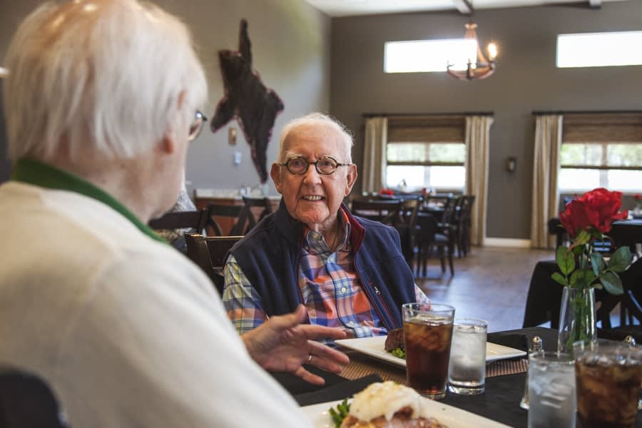 A group of senior individuals enjoying a meal and engaging in conversation at a restaurant.