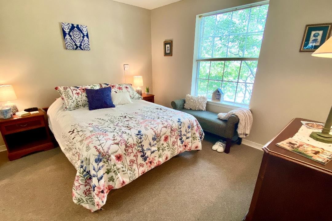 A cozy bedroom with a floral-themed bedspread and bright window.