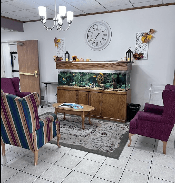 A cozy lobby area with a fish tank, armchairs, and decorative elements.