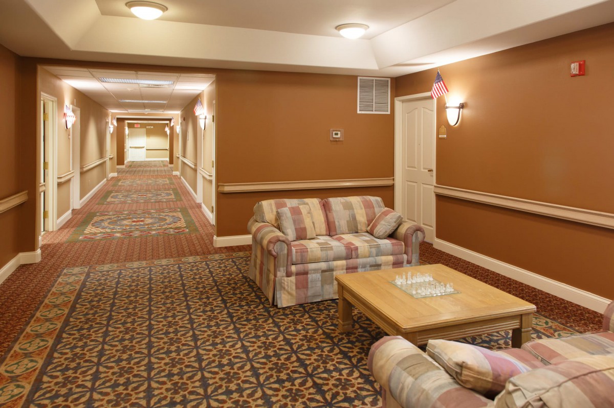 A hotel hallway featuring a seating area with couches and a patterned carpet.