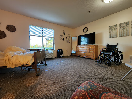 A spacious hospital room featuring a bed, wheelchair, and a view through the window.