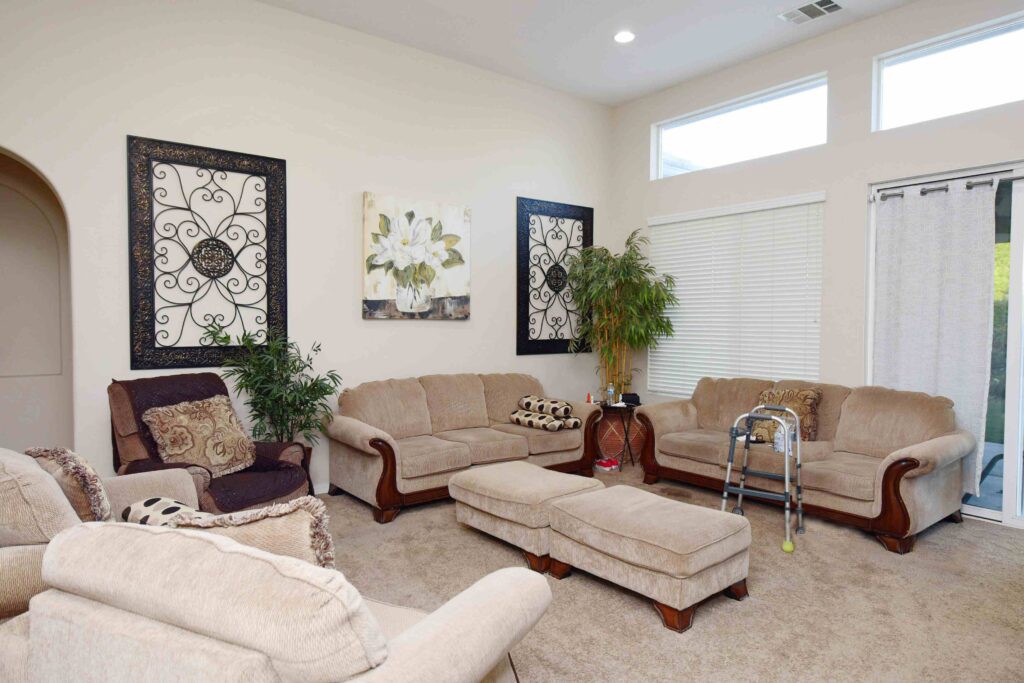 A cozy living room with beige sofas, decorative wall art, and indoor plants.