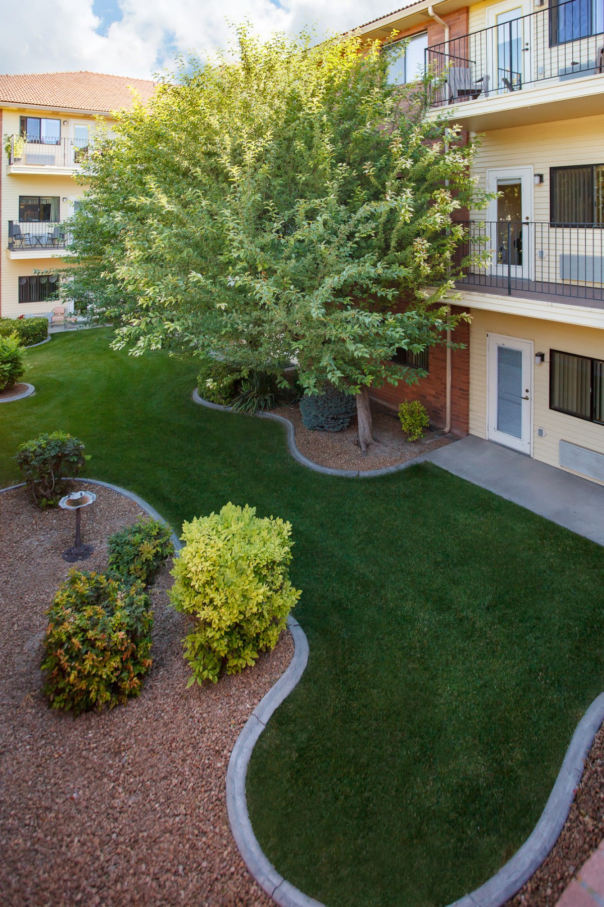 A well-maintained apartment complex with lush greenery and neatly trimmed bushes.
