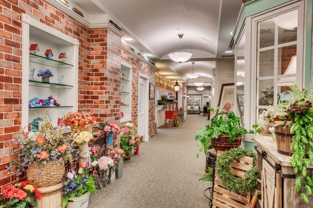 A charming indoor flower shop with brick walls and a variety of plants and flowers displayed along a hallway.