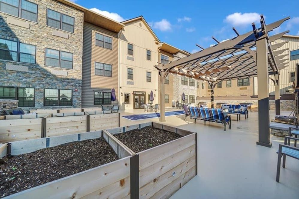 A modern building with an outdoor patio area featuring seating and planters under a clear blue sky.