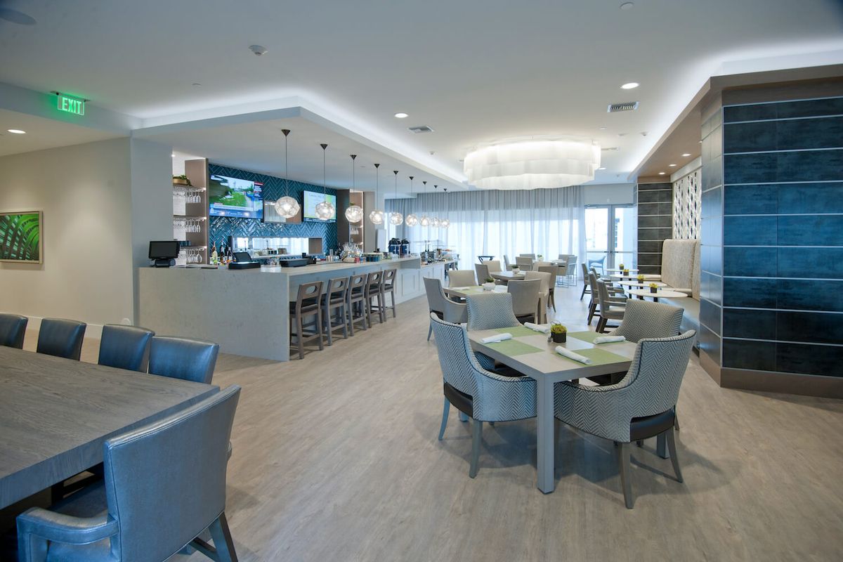 A modern restaurant interior with a bar area and dining tables arranged in a contemporary setting.