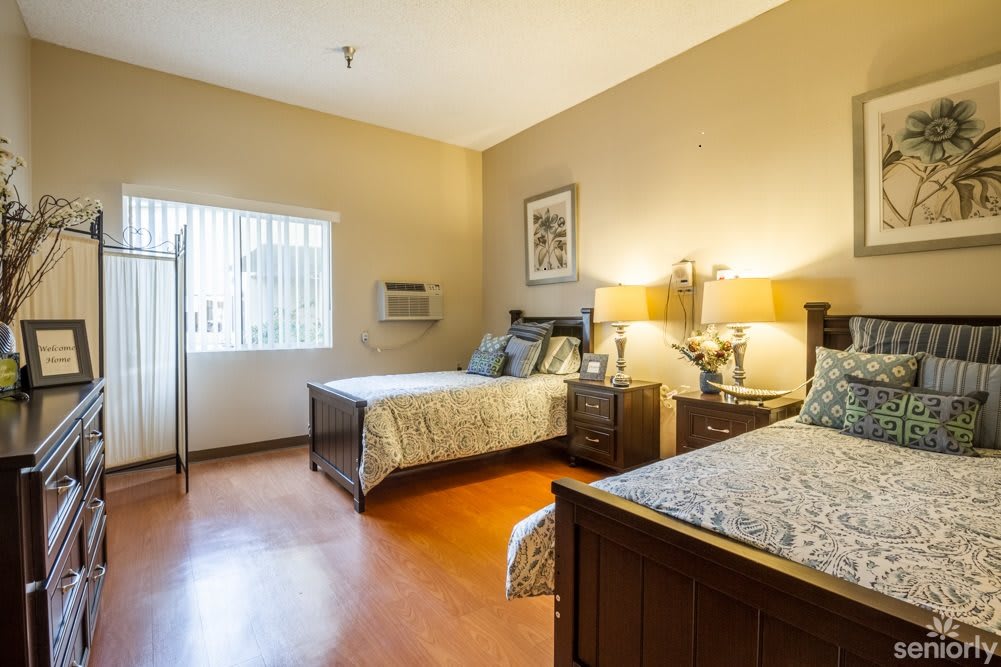 A spacious bedroom with two neatly made beds, wooden furniture, and soft lighting from table lamps.