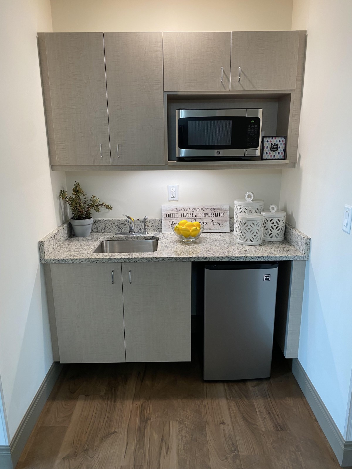 A compact kitchenette with a microwave, sink, and mini fridge.