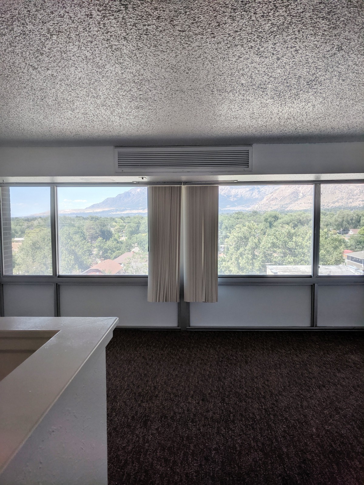 An empty room with large windows providing a view of the mountains.