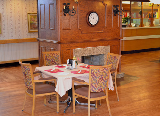 A cozy restaurant dining area featuring a table set for a meal, surrounded by wooden furniture and a charming wall clock.