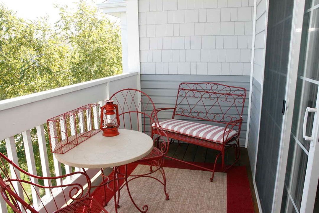 Cozy balcony with red outdoor furniture and a lantern.