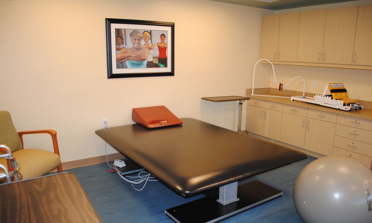 An examination room with a medical table and framed artwork on the wall.