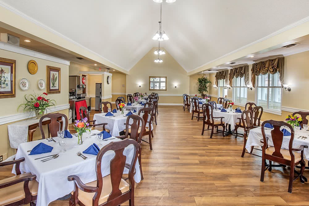 A spacious and elegant dining room with neatly arranged tables and chairs, featuring a warm interior design.