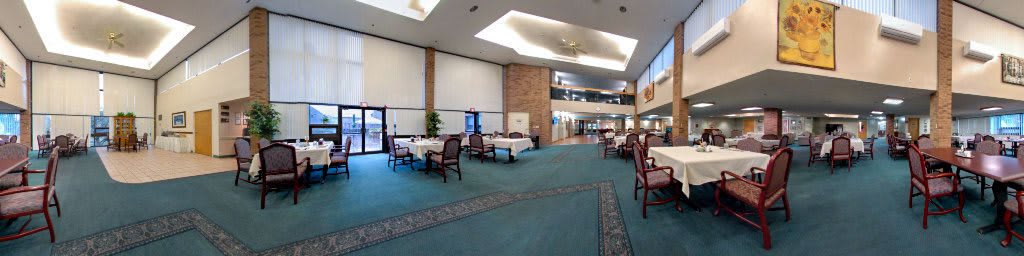 A spacious dining area with tables and chairs, featuring modern design and carpeted flooring.