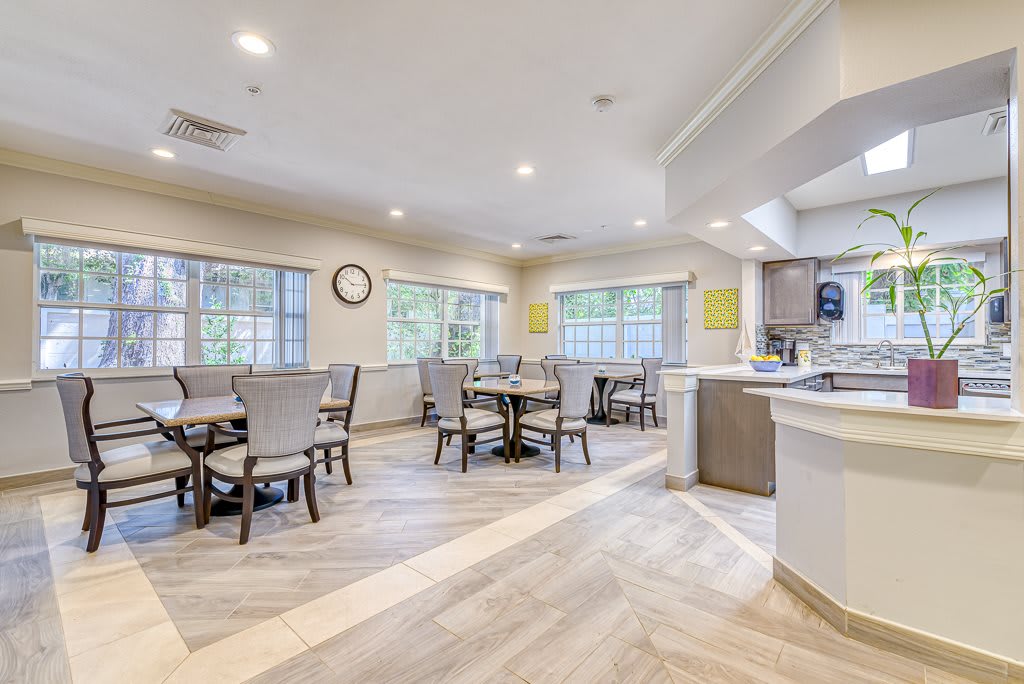 A modern dining area with multiple tables and chairs, featuring large windows and a clean, bright interior.