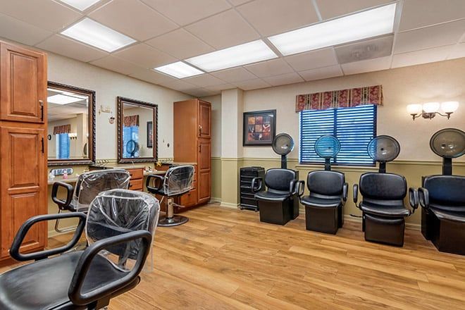 An empty hair salon with chairs, mirrors, and hair dryers.