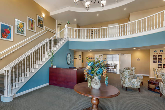 A welcoming lobby area featuring a grand staircase, a reception desk, and a table adorned with a floral arrangement.