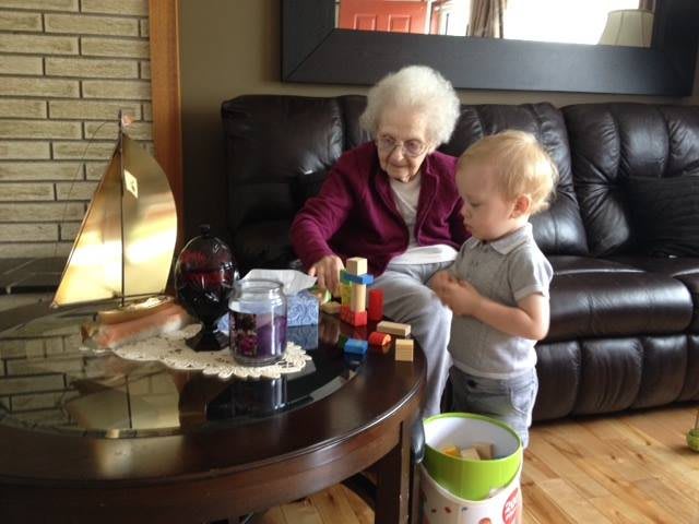 An elderly person and a child playing with blocks in the living room.