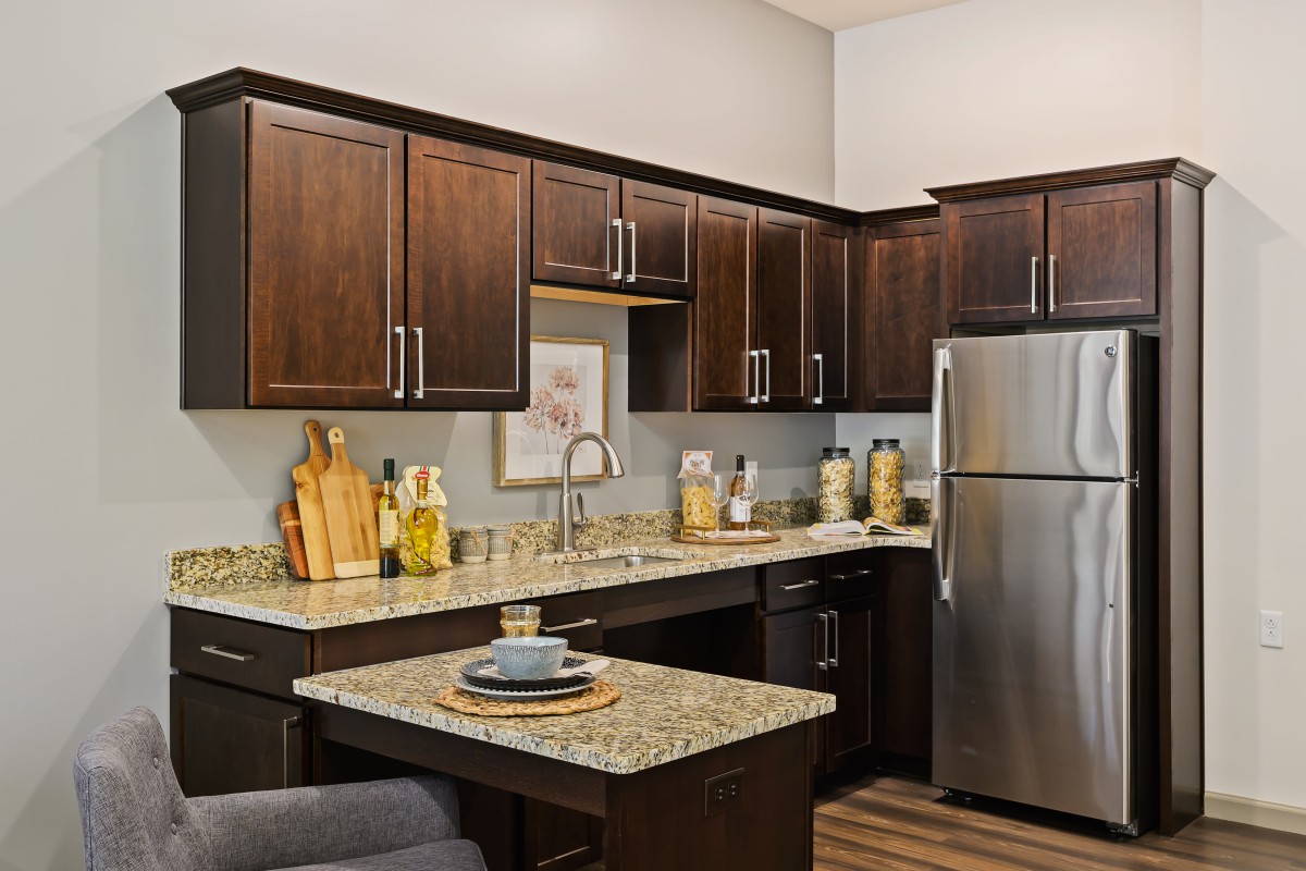A modern kitchen with dark wood cabinets, granite countertops, and stainless steel appliances.