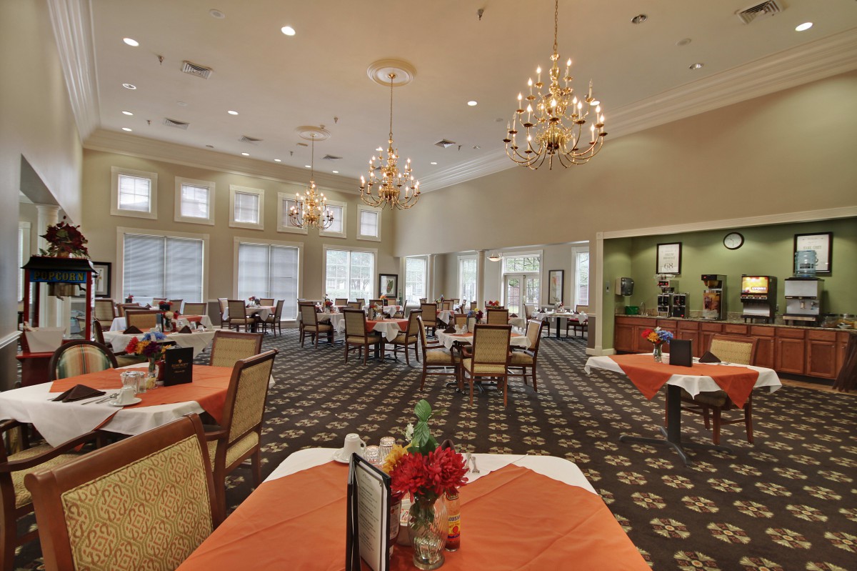 A spacious dining room with elegant chandeliers, neatly arranged tables and chairs.